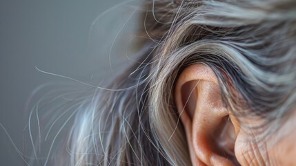 A strand of grey hair peeking out from behind the ear marking the passage of time. .