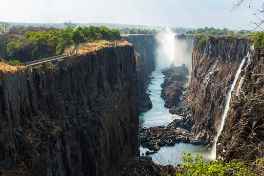 Victoria Falls viewed from the Zambian side, deep gorge with vertical sides, waterfall with torrents of white water.
