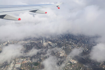 London photographed among the clouds on the window of a passenger flight.