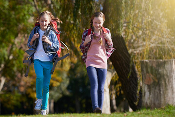 Girls, nature and backpack for hike, walk and exercise for outdoor travel holiday. Fitness, fun and hobby for excited children friends, camping and vacation or weekend trip to countryside of England
