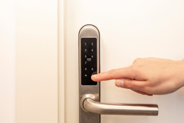 Close-up image of a person's finger entering a code on a security keypad to unlock a door, focusing on safety and privacy