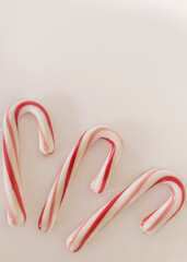 Three peppermint candy canes on a white background with copy space