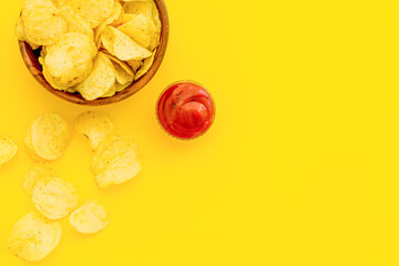 Wooden bowl of crispy potato chips, top view. Fast food and snack background