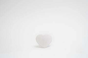 White heart on a white background in the center of the frame. Minimalism. Copy space. Concept of Valentine's Day or wedding romantic theme.