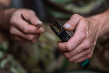 Close-up shot of hands of Ukrainian military man loads the assault rifle magazine with cartridges