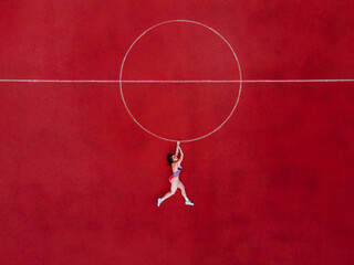 Abstract aerial shot of woman in swimwear hanging holding a circle on basketball field