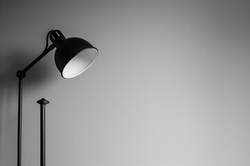 A minimalist, modern black lamp against a white wall, creating a contrast of light and shadow