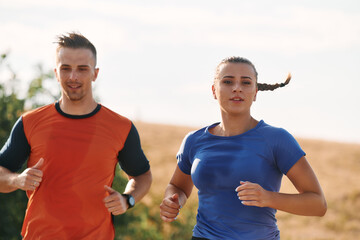 Fototapeta premium A couple dressed in sportswear runs along a scenic road during an early morning workout, enjoying the fresh air and maintaining a healthy lifestyle