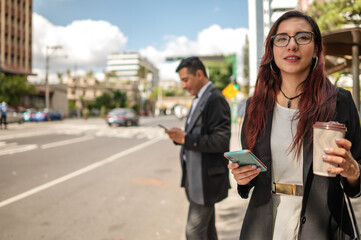 businesswoman in the financial center of the city with a cell phone and a cup of coffee in her...