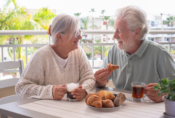 Smiling bonding senior retired couple looking into each other's eyes enjoy breakfast together...