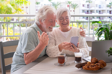 Video call concept. Happy bonding senior retired couple using mobile phone technology for online webcam connection, enjoying carefree moments together with distant family