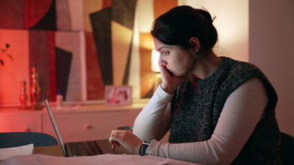 Woman in front of laptop at home in the evening. 30s person browsing internet, studying or working...