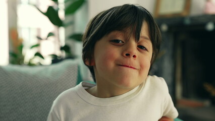 Young 5 year old boy portrait seated at home couch, close-up face of joyful male caucasian kid