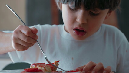 Young Boy Delicately Selecting Strawberry Slices from Cheesecake/ Enjoying Sweet Dessert with Fork...