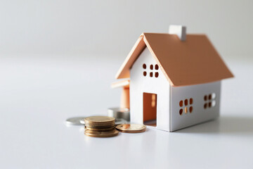 Hand holding a coin and house model on blue background with copy space,ç