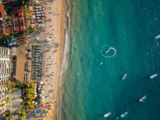 Boat doing circles in the ocean below near popular beach in Puerto Vallarta Mexico. - obrazy, fototapety, plakaty
