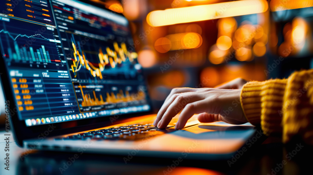 Wall mural person analyzing financial data on a laptop with stock market graphs on the screen in a dimly lit wo
