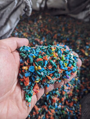 Hand holding recycled plastic chips as raw material in production. Close up. Selective focus.