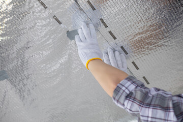 Worker tapping vapor barrier joints on ceiling. - obrazy, fototapety, plakaty