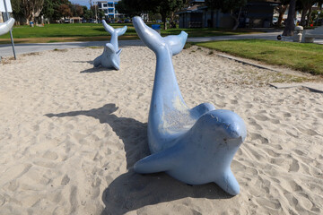 A Beach Playground in San Diego, California, with concrete bench dolphins in the sand.