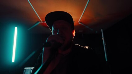 POV footage man with a bald shaved head with black cap and beard, is creating music in a recording studio. An aspiring artist is crafting a melody and rehearsing for an upcoming performance.