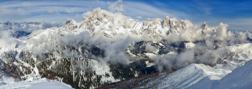 Winter Majesty: Sunlit Pale di San Martino Peaks Amidst Clouds - Aerial Panoramic View.