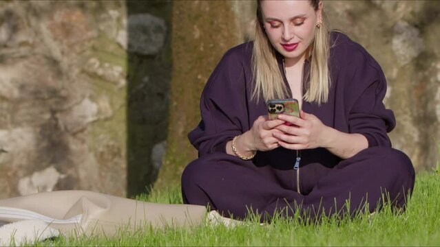 Young Woman is Using her Mobile Phone in Nature