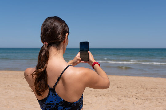 Healthy woman in sportswear taking a picture of the beach while playing sports