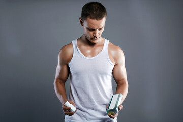 bodybuilder eating pills, steroids. Handsome Fitness Boy with medicine bottle - 787458745