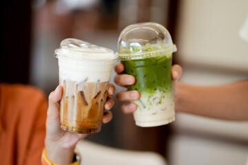 Close up and selective focus glass of ice coffee and ice matcha green tea on hands of teenage...