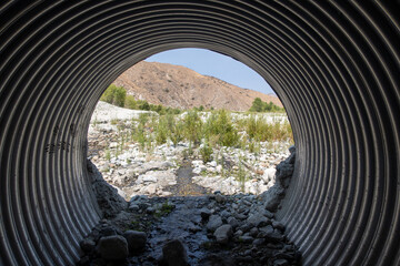 A Culvert under a Road in a Desert Environment with a view of the Exit