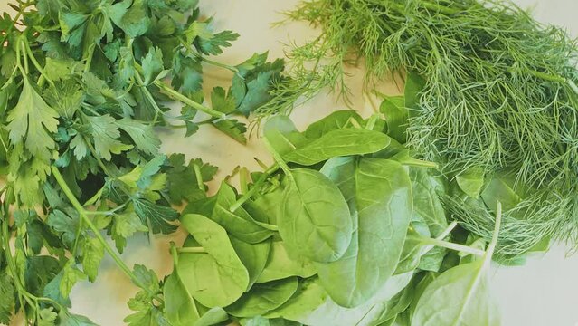 Dill, parsley and baby spinach leaves on a wooden board. Rotating. Close-up. Fresh, raw herbs, spices. Vegan, fitness ingredients. High quality 4k footage