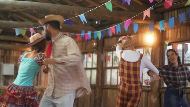 Couples Engaging in Square Dancing at Joyful Festa Junina Celebration. Revelers in Traditional Brazilian Costumes Twirling in a Rustic Barn Setting