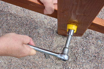 Ratchet socket wrench is used to tighten bolt when assembling outdoor furniture. - obrazy, fototapety, plakaty