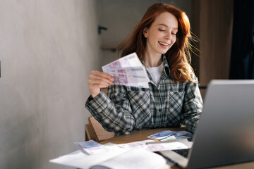 Portrait of happy excited young businesswoman holding fan of cash money euro banknotes celebrate, dance, success career, lottery jackpot game winner, big income, wealth at home office workplace desk.