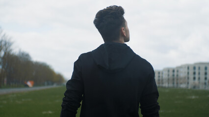 A young man walks forward in the rain and looks back at the camera. Moving forward. Motivation