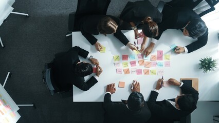 Top down ariel view of professional business team use colorful sticky notes brainstorming idea at meeting room. Diverse group share financial plan or project and point at whiteboard. Directorate. - obrazy, fototapety, plakaty