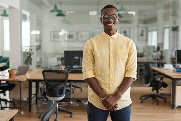Smiling young African businessman standing in a modern office