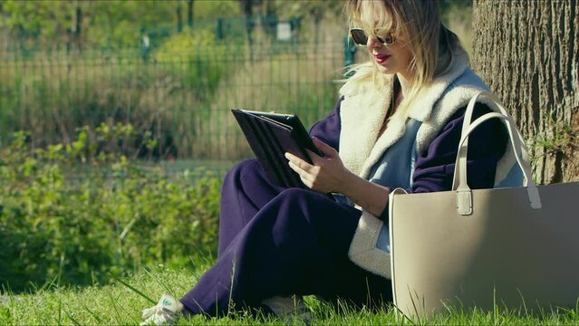 Young Woman using Digital E book on Grass in Nature