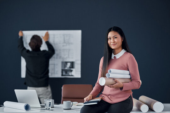 Architect, woman and smile in portrait with roll of sketch paper, documents and design project. Person, happy and Asian property developer with blueprint for construction, building or job in Jakarta