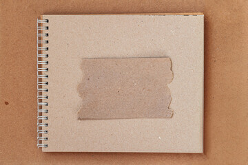 Frame of craft paper with torn edges on natural background of sketchbook on spiral