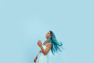 Girl, earphones and phone for song in studio, website and online for streaming playlist on blue background. Female person, mockup space and dancing with energy, kpop and app for music in profile