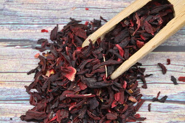 Karkade tea. Hibiscus tea leaves in wooden scoop isolated on wooden background. File contains clipping path. Top view.