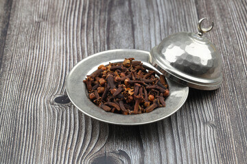 Dry cloves in wooden scoop isolated on wooden background with clipping path. Top view. Flat lay. selective focus.