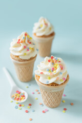 Wafer cones stuffed with mini cakes and buttercream frosting with colorful sugar sprinkles, ice cream alternative dessert