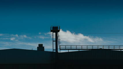 view of the roof of an industrial building in a dark setting and blue sky  - 787481128