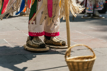 Feet of a dancer from the dance of the old men, a typical Mexican dance. Using sandals, clothing, and in front of him a basket to receive coins.