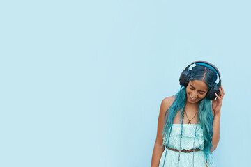 Woman, headphones and laugh with music, mockup space and blue wall background on campus. Student,...