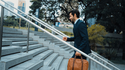 Skilled business man walking up stairs at park or city while holding bag in the hand Professional...