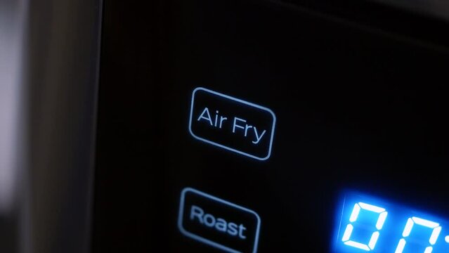 Close-up of a modern air fryer, programme touch button flashing while setting up. Concept for fast air fry home cooking, healthy eating, lower fat, versatility, time saving and cheaper to run.